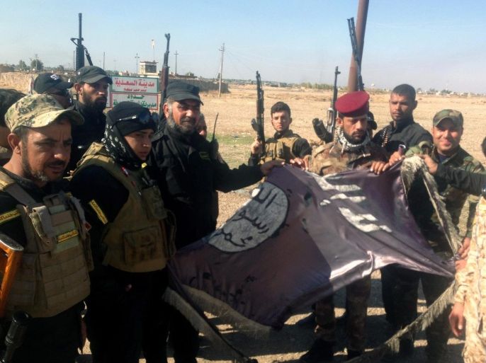Iraqi soldiers carry a torn-up Islamic state flag after they seized Sa'adiya town northeast of Baghdad, Iraq, 24 November 2014. Local media reports that Iraqi Army backed by Shiite militias and airstrikes carried out by the international anti-IS coalition retook the town of Sa'adiya in the eastern province of Diyala from Islamic State fighters.  EPA/STR BEST QUALITY AVAILABLE