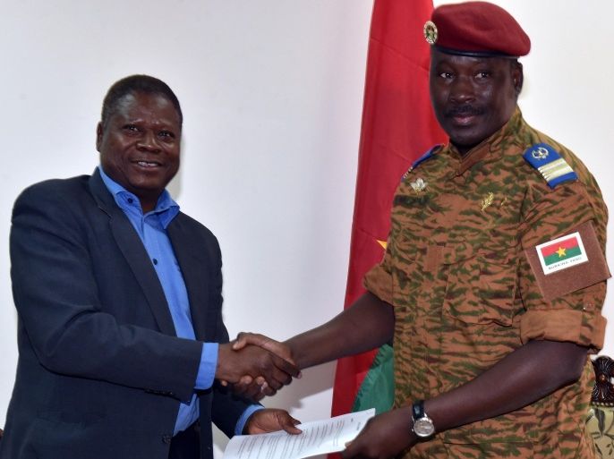 Henry Ye, president of the commission representing the main power players (L) hands the transition charter to Burkina Faso's army-appointed leader, Lieutenant-Colonel Isaac Zida during a meeting at the Economic and Social Council headquarters in Ouagadougou, Burkina Faso, on November 14, 2014. Burkina Faso's army on November 13, 2014 reached an agreement with opposition parties, civil groups and religious leaders for a transition to civilian rule, almost two weeks after the ouster of president Blaise Compaore. The different factions 'unanimously voted' in favour of a transition charter, said Henry Ye, president of the commission representing the main power players in the west African country. Under the deal, an interim civilian president will be chosen by a special electoral college, delegates at the talks said. AFP PHOTO / ISSOUF SANOGO