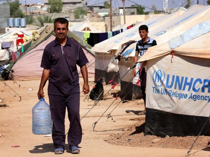 TO GO WITH STORY BY: Emilienne MalfattoA displaced Iraqi, who had fled their homes after an offensive led by the Islamic State (IS) jihadist group, carries water near tents provided by the United Nations High Commission for Refugees (UNHCR) at the Ayden camp, an extension of the larger Aliama camp, in the town of Khanaqin, 160 kms northeast of Baghdad, on September 27, 2014. Families arriving at the northern camp of Aliama without men are forced to explain their absence and prove they are not jihadist fighters, even by providing certificates if they are no longer alive. AFP PHOTO/ SAFIN HAMED
