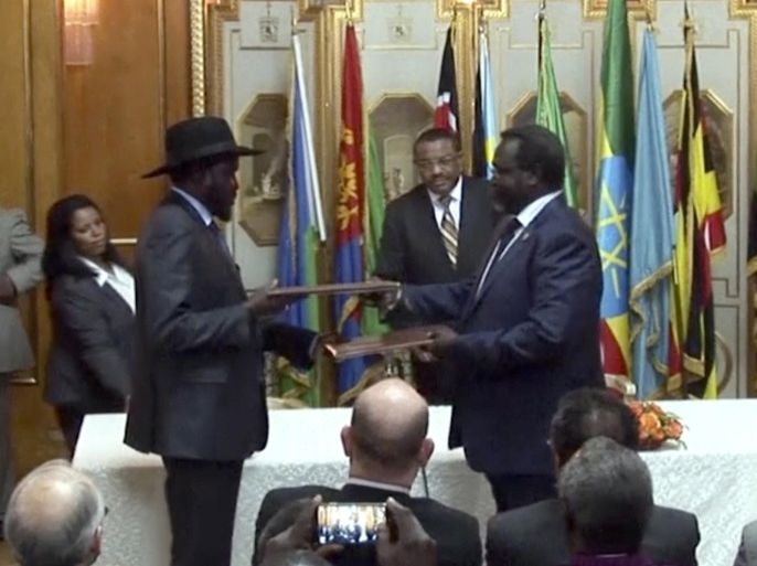 In this Friday, May 9, 2014 image made from video, South Sudan's President Salva Kiir, center left, and rebel leader Riek Machar, center right, exchange the signed documents in Addis Ababa, Ethiopia. The South Sudan's president has reached a cease-fire agreement with the rebel leader, an African regional bloc said Friday, after a vicious cycle of revenge killings drew international alarm. (AP Photo/AP Video)
