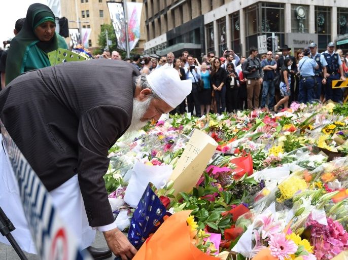 A Muslim man and a relative join thousands of Sydneysiders in laying flowers near the Lindt chocolate cafe in Martin Place following last nights dramatic siege in Sydney, Australia, 16 December 2014. Police stormed a central Sydney cafe after a fringe Islamist with a criminal record allegedly held customers and staff hostage at gunpoint for more than 16 hours. The suspected gunman, who came to Australia as a refugee from Iran in 1996, was killed as well as two hostages. EPA/DEAN LEWINS AUSTRALIA AND NEW ZEALAND OUT