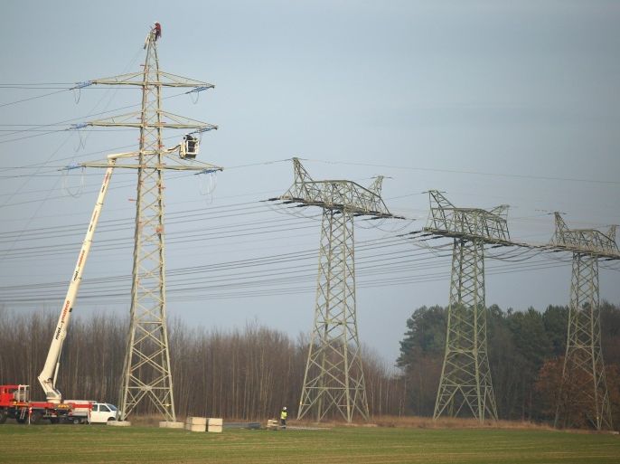 LUEBBEN, GERMANY - DECEMBER 04: Workers prepare an electricity transmission tower, also called an electricity pylon, in order to hang electricity transmission cables from it on December 4, 2014 near Luebben, Germany. Germany is expanding its electricity grid as part of its large-scale shift from conventional coal, gas and nuclear-based energy production to renewable sources, especially wind and solar.