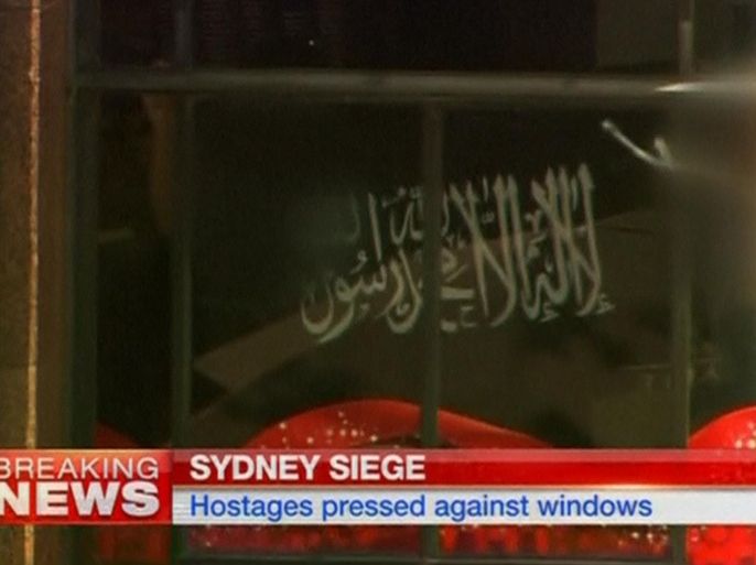 A black flag with white Arabic writing is held up at the window of the Lindt cafe, where hostages are being held, in this still image taken from video from Australia's Seven Network on December 15, 2014. Dozens of hostages were trapped inside the central Sydney cafe on Monday, with local television showing some being forced to hold up a black flag with white Arabic writing in the window, raising fears of an attack linked to Islamic militants. REUTERS/Reuters TV via Seven Network/Courtesy Seven Network (AUSTRALIA - Tags: CIVIL UNREST CRIME LAW) ATTENTION EDITORS - THIS IMAGE HAS BEEN SUPPLIED BY A THIRD PARTY. IT IS DISTRIBUTED, EXACTLY AS RECEIVED BY REUTERS, AS A SERVICE TO CLIENTS. NO SALES. NO ARCHIVES. FOR EDITORIAL USE ONLY. NOT FOR SALE FOR MARKETING OR ADVERTISING CAMPAIGNS. AUSTRALIA OUT. NO COMMERCIAL OR EDITORIAL SALES IN AUSTRALIA. NO ACCESS AUSTRALIA / .COM.AU INTERNET SITES / ANY INTERNET SITE OF ANY AUSTRALIAN BASED MEDIA ORGANISATIONS / AUSTRALIAN NVO CLIENTS / SMH.COM.AU / NEWS.COM.AU