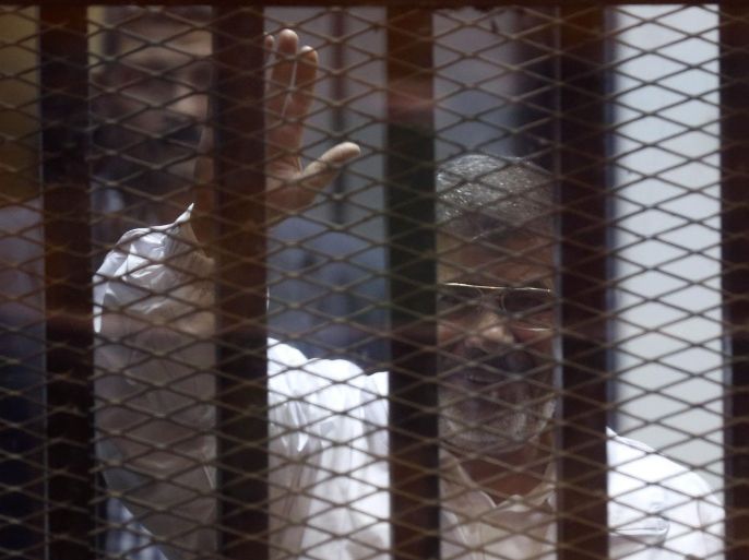 Former Egyptian President Mohamed Mursi waves as he enters for his trial with other Muslim Brotherhood members at a court in the outskirts of Cairo December 14, 2014. Egypt declared Mursi's Muslim Brotherhood a banned terrorist organization last December and Egyptian courts have sentenced hundreds of the group's members to death in mass trials that have drawn strong international criticism. REUTERS/Asmaa Waguih (EGYPT - Tags: POLITICS CRIME LAW CIVIL UNREST)