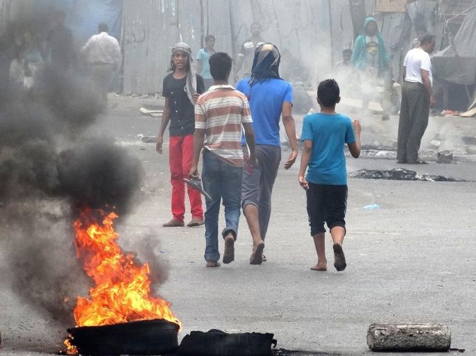 Young Yemeni protesters walk past burning tires during a demonstration demanding renewed independence in the southern city of Aden on December 15, 2014. A separatist activist was among two people shot dead in southern Yemen, as secessionists staged a day of civil disobedience, witnesses and activists said. Most businesses and schools in Aden were closed in response to the call for the demonstration to demand the secession of the formerly independent south. AFP PHOTO/ STR