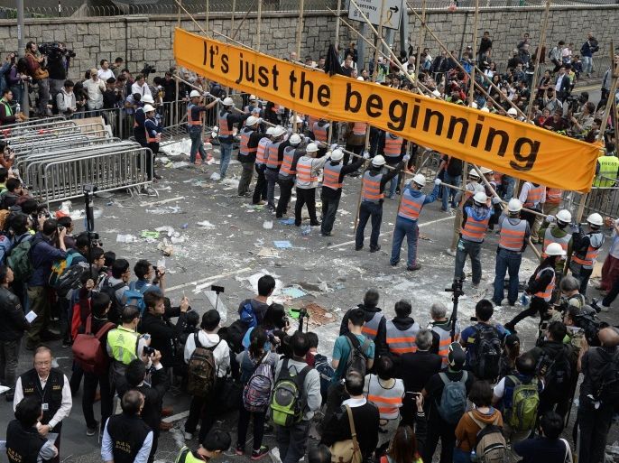 Members of the media and onlookers watch as workers (C) dismantle barricades built by pro-democracy demonstrators at the main protest site in the Admiralty district in Hong Kong on December 11, 2014. Bailiffs on December 11 started dismantling barricades at Hong Kong's main protest site after more than two months of pro-democracy rallies that demonstrators say have redefined the city's vexed relationship with Beijing. AFP PHOTO / DALE DE LA REY