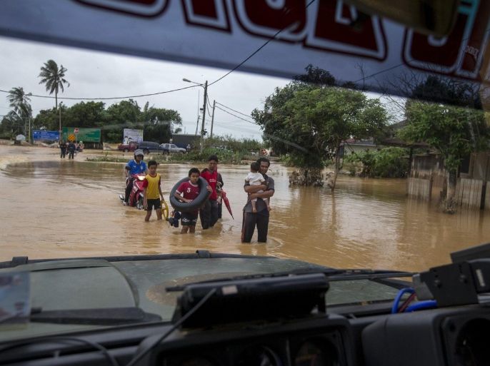 People carry their belongings as they evacuate through a flooded street on the outskirt of Kota Bharu in Kelantan December 29, 2014. The worst flooding in Malaysia in more than a decade has killed 10 people and forced nearly 160,000 from their homes and more rain is expected, authorities said on Sunday. REUTERS/Athit Perawongmetha (MALAYSIA - Tags: ENVIRONMENT DISASTER)