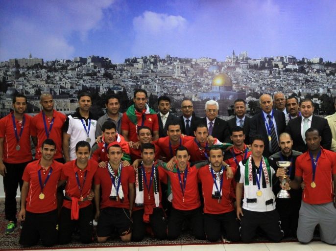 Palestinian president Mahmud Abbas (C) receives, in his office in the West Bank city of Ramallah on June 1, 2014, the Palestinian national football team which won the AFC Challenge Cup. Palestine qualified for their maiden Asian Cup appearance with a 1-0 win over injury-hit Philippines in the final of the AFC Challenge Cup in Maldives. AFP PHOTO/ABBAS MOMANI
