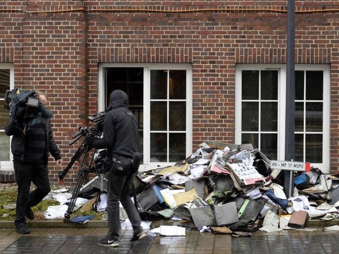 Members of a television crew are seen beside burned files and documents in front of a building of German newspaper Hamburger Morgenpost in Hamburg January 11, 2015. The building was the target of an arson attack and two suspects were arrested, police said on Sunday. Like many other German newspapers, Hamburger Morgenpost has printed cartoons of French satire magazine Charlie Hebdo after the deadly attack on Wednesday in Paris. A police spokeswoman said that an incendiary device was thrown at the newspaper building in the night and documents were burned inside. REUTERS/Fabian Bimmer (GERMANY - Tags: CIVIL UNREST CRIME LAW MEDIA)