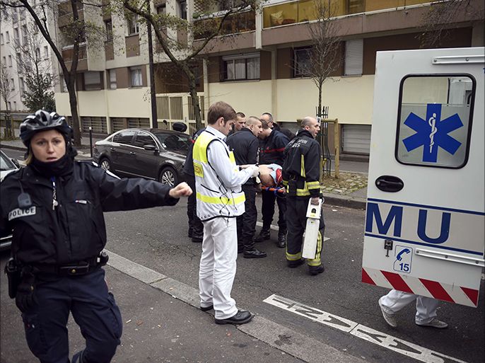 Firefighters carry an injured man on a stretcher in front of the offices of the French satirical newspaper Charlie Hebdo in Paris on January 7, 2015, after armed gunmen stormed the offices leaving at least 10 people dead. AFP PHOTO / MARTIN BUREAU