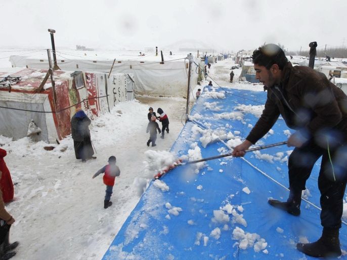 A Syrian refugee removes snow from tents during snowfall at a makeshift settlement in Bar Elias, in the Bekaa valley, January 7, 2015. A storm buffeted the Middle East with blizzards, rain and strong winds on Wednesday, keeping people at home across much of the region and raising concerns for Syrian refugees facing freezing temperatures in flimsy shelters. REUTERS/Mohamed Azakir (LEBANON - Tags: SOCIETY IMMIGRATION CIVIL UNREST POVERTY ENVIRONMENT DISASTER)
