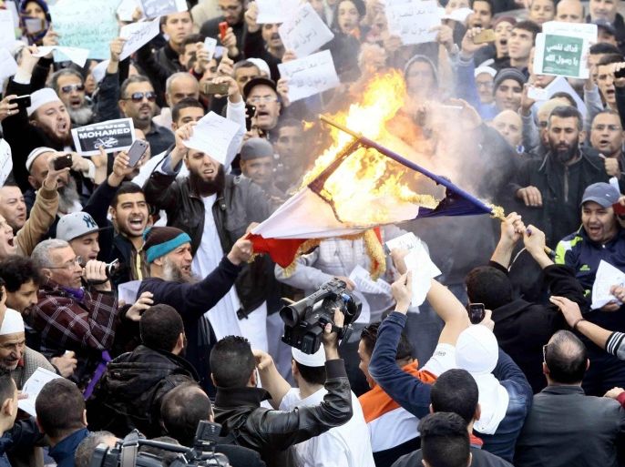 Demonstrators burn the French national flag after Friday prayers in Algiers January 16, 2015. Police clashed with demonstrators in Algiers after rioting broke out at the end of a protest against the publication of cartoons depicting the Prophet Mohammad in the French satirical magazine Charlie Hebdo. REUTERS/Ramzi Boudina (ALGERIA - Tags: POLITICS CIVIL UNREST RELIGION)