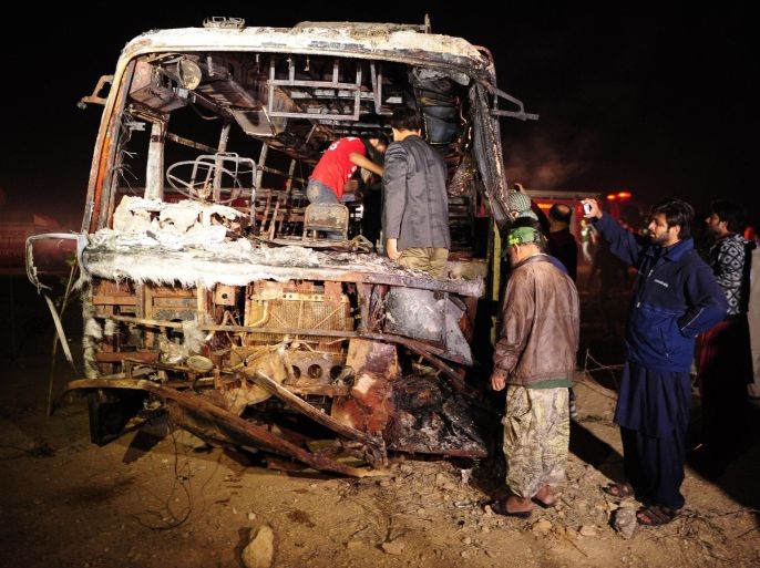 Pakistani volunteers search for victims inside a burnt out passenger bus after it collided with an oil tanker along the Super Highway near Karachi early on January 11, 2015. At least 30 people were killed when an oil tanker apparently speeding in the wrong direction down a Pakistan road crashed into a passenger bus early January 11, igniting a fierce blaze, police said. AFP PHOTO/ Asif HASSAN