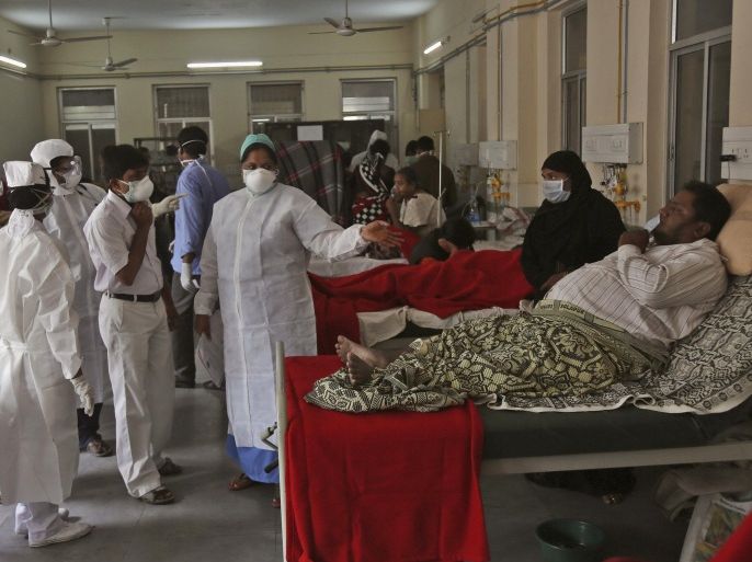 Indian doctors, nurses and patients' family members wear masks inside a Swine flu ward where patients suspected with H1N1 flu are being treated at Gandhi Hospital in Hyderabad, India, Wednesday, Jan. 21, 2015. According to local reports, nine people died at the state-run hospital. (AP Photo/Mahesh Kumar A.)