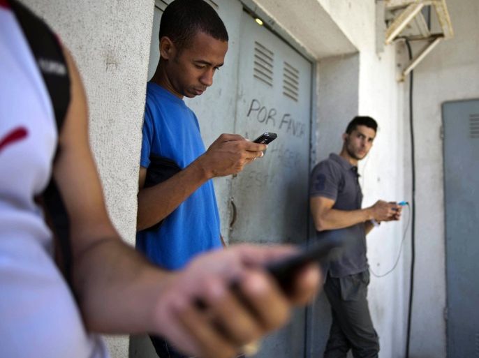 FILE - In this April 1, 2014 file photo, students stand outside a building to find an Internet signal for their phones in Havana, Cuba. In programs revealed by the Associated Press in 2014, USAID secretly created a primitive social media program called ZunZuneo, staged a health workshop to recruit activists and infiltrated Cuba’s hip-hop community. Those programs were part of a grassroots campaign aimed at undermining the Castro government through the citizenry, rather than directly targeting political leaders. (AP Photo/Ramon Espinosa, File)
