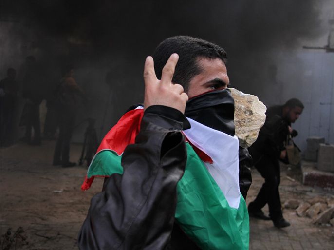 شاب فلسطيني ملثم يستلهم تجربة الانتفاضة في تظاهرة ضد أونروا