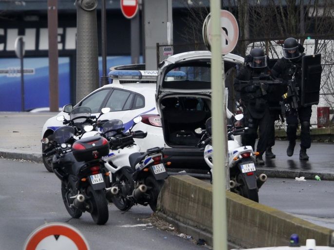 French intervention police are seen at the scene of a hostage taking at a kosher supermarket (seen in rear) near the Porte de Vincennes in eastern Paris January 9, 2015, following Wednesday's deadly attack at the Paris offices of weekly satirical newspaper Charlie Hebdo by two masked gunmen who shouted Islamist slogans. Several people were taken hostage at a kosher supermarket in eastern Paris on Friday after a shootout involving a man armed with two guns, a police source said. There were unconfirmed local media reports that the man was the same as the one suspected of killing a policewoman in Montrouge, a southern suburb of Paris on Thursday. REUTERS/Charles Platiau (FRANCE - Tags: CRIME LAW MILITARY) ATTENTION EDITORS FRENCH LAW REQUIRES THAT VEHICLE REGISTRATION PLATES ARE MASKED IN PUBLICATIONS WITHIN FRANCE