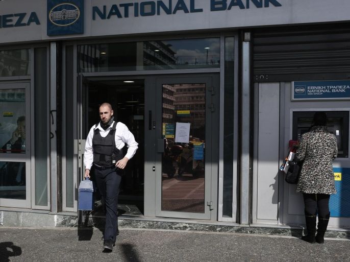 A security guard carries a box of cash out of a National Bank of Greece bank branch in Athens, Greece, on Thursday, Feb. 19, 2015. Germany rebuffed Greece's request for an extension of its aid program, saying the Greek offer doesn't meet the euro region's conditions for continuing aid.