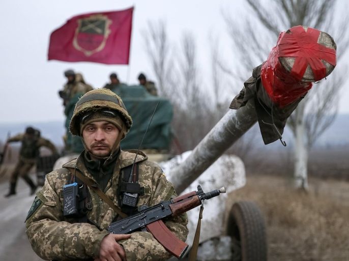 A member of the Ukrainian armed forces stands guard as a convoy of the Ukrainian armed forces including armoured personnel carriers, military vehicles and cannons prepare to move as they pull back from the Debaltseve region, in Paraskoviyvka, eastern Ukraine, February 26, 2015. Ukrainian troops towed artillery away from the front line in the east on Thursday, a move that amounted to recognising that a ceasefire meant to take effect on Feb. 15 was holding at last. REUTERS/Gleb Garanich (UKRAINE - Tags: POLITICS CIVIL UNREST MILITARY CONFLICT)