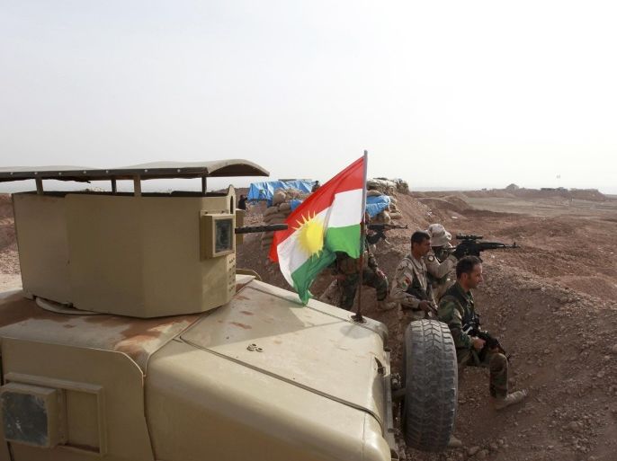 A Kurdish flag is seen next to Peshmerga fighters taking position with their weapons on the frontline against the Islamic State, on the outskirts of Mosul January 26, 2015. Kurdish Peshmerga fighters are digging trenches and building defense berms in Wadi al-Ghorab (Valley Of The Crows), less than 2 km away from the IS-held Sultan Abdullah village, which demarcates the new border of their autonomous region. The Kurds have enjoyed de facto self rule since the first Gulf War in 1991. They are now closer than ever to achieving their dream of full independence. Yet they are menaced by the deadly ambitions of the Islamic caliphate across the frontline. Picture taken January 26, 2015. REUTERS/Azad Lashkari (IRAQ - Tags: CIVIL UNREST CONFLICT MILITARY POLITICS)