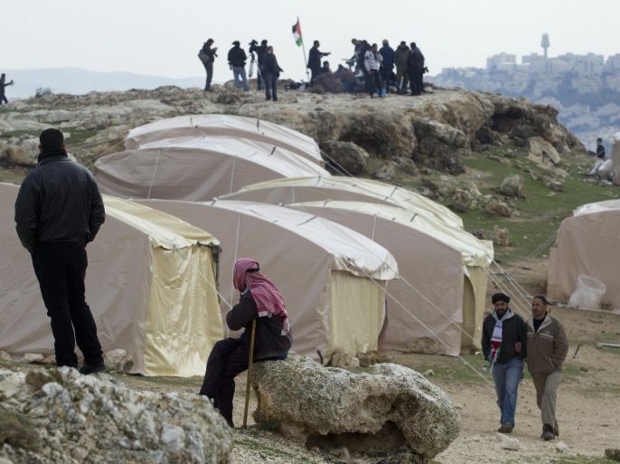 A Bedouin man sitting near the newly-erected tents that make up what Palestinians call the new 'outpost settlement' of Bab al-Shams (Gate of the Sun), 11 January 2013, set-up outside the Palestinian West Bank village of Ez Za'im in the contentious area east of Jerusalem, in the West Bank known as E1, where part of the sprawling Jewish settlement o Ma'ale Adumim is seen, behind. Israel intends to build thousands of housing units here, drawing severe criticism from many countries in clouding the US and Europe.