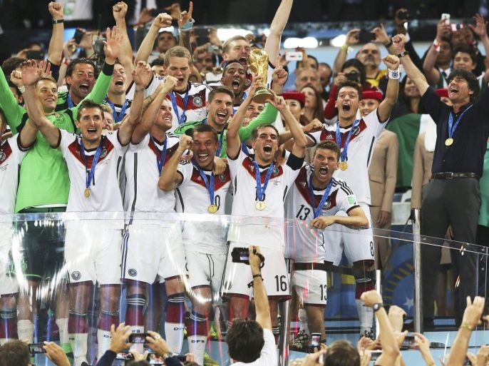 German captain Philipp Lahm lifts the World Cup trophy after winning the FIFA World Cup 2014 final between Germany and Argentina at the Estadio do Maracana in Rio de Janeiro, Brazil, 13 July 2014. At right is German head coach Joachim Loew. (RESTRICTIONS APPLY: Editorial Use Only, not used in association with any commercial entity - Images must not be used in any form of alert service or push service of any kind including via mobile alert services, downloads to mobile devices or MMS messaging - Images must appear as still images and must not emulate match action video footage - No alteration is made to, and no text or image is superimposed over, any published image which: (a) intentionally obscures or removes a sponsor identification image; or (b) adds or overlays the commercial identification of any third party which is not officially associated with the FIFA World Cup) EPA/Marcelo Sayao