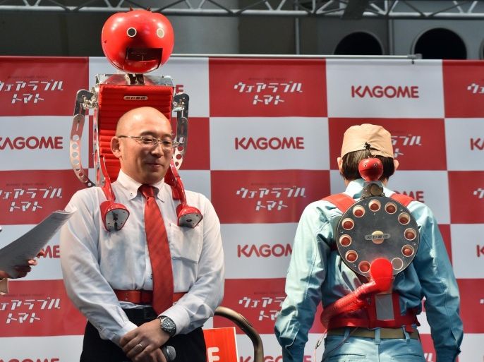 Japan's food company Kagome employee Shigenori Suzuki (L) displyas the newly developed tomato dispenser for marathon runner 'Tomachan' during a demonstration ahead of this weekend's Tokyo marathon in Tokyo on February 19, 2015. The hands free tomato eating machine was developed by a Japanese artist Nobumichi Tosa (unseen in this picture) and Tosa also developed a compact one 'Mini-Tomachan' (R). AFP PHOTO / Yoshikazu TSUNO