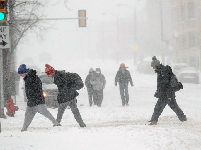 Students fight the snow and wind while crossing the street near the Marquette University campus, Sunday, Feb. 1, 2015, in Milwaukee. A slow-moving winter storm blanketed a large swath of the Plains and Midwest in snow Sunday, forcing the cancellation of more than 1,500 flights and making roads treacherous. (AP Photo/Milwaukee Journal-Sentinel, Michael Sears)
