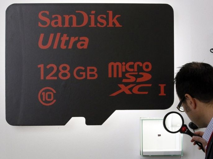 A visitor looks at a SanDisk microSD card at the Mobile World Congress in Barcelona February 25, 2014. SanDisk introduced what they say is the world's highest capacity microSDXC memory card with a 128GB capacity at the mobile industry's largest annual gathering. REUTERS/Gustau Nacarino (SPAIN - Tags: BUSINESS TELECOMS)