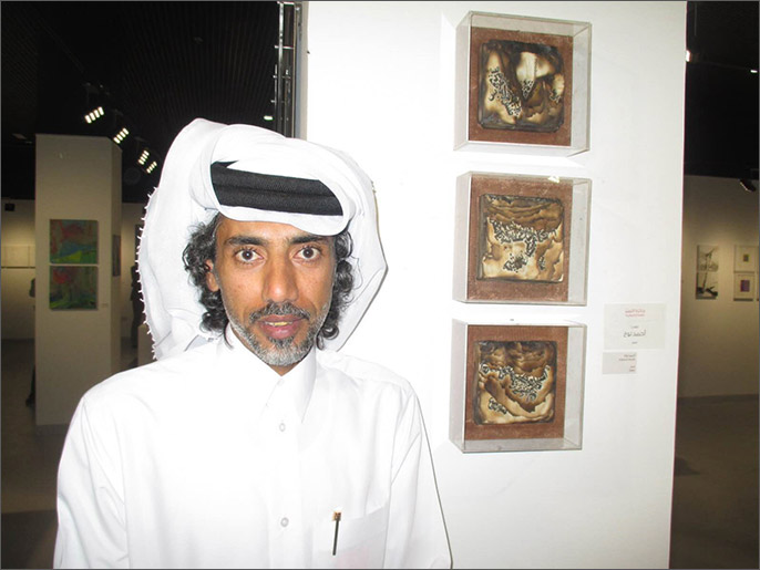 ‪الفنان القطري أحمد نوح أمام عمله المتوج بجائزة التميز‬ (الجزيرة)