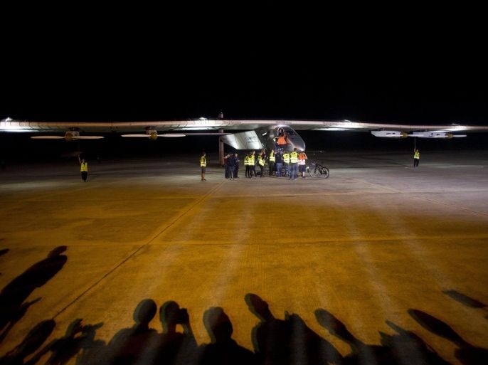 Support crew members of Solar Impulse 2, the world's only solar powered aircraft, stand near the plane, before it took off from the Mandalay International Airport in Myanmar on March 30, 2015. Solar Impulse 2 took off from Myanmar's second biggest city of Mandalay early on March 30 and headed for China's Chongqing, the fifth flight of a landmark journey to circumnavigate the globe powered solely by the sun. AFP PHOTO / YE AUNG THU