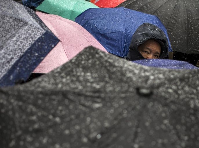 A man looks past commuters who are holding umbrellas during snowfall in Times Square, Midtown New York March 20, 2015. Spring arrives in the winter-weary U.S. Northeast on Friday but the weather forecast was for more of the same: another half-foot of snow for parts of the region, prompting widespread flight cancellations and early school dismissals. REUTERS/Adrees Latif TPX IMAGES OF THE DAY