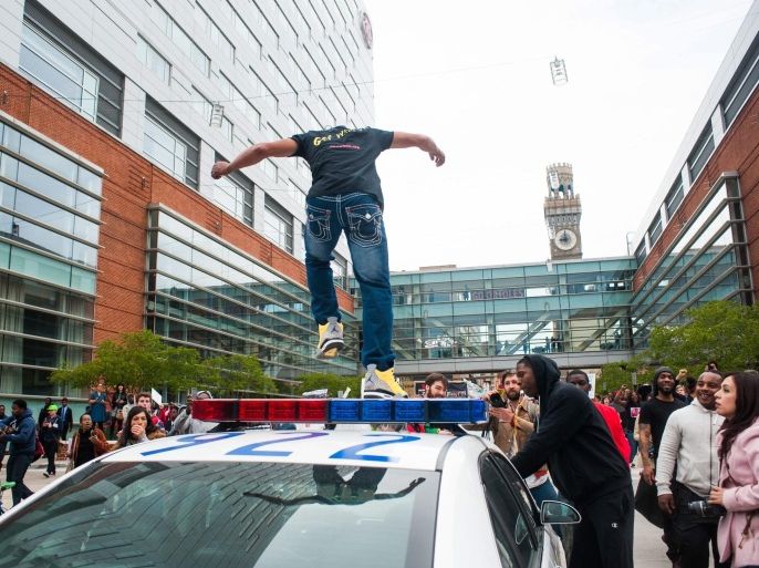 A man jumps on a Baltimore Police car in front of Camden Yards to protest the death of Freddie Gray in Baltimore, Maryland, USA, 25 April 2015. Gray died of spinal cord injuries on 19 April while in police custody; the US Justice Department announced that they are launching their own investigation into the case.
