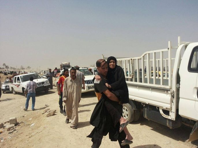 A man carries his elderly mother as displaced people from Ramadi wait for the approval of the security forces to enter Baghdad, near Bzabz bridge outside Baghdad, Iraq, Friday, April 17, 2015. Islamic State extremists were reported Thursday to be closing in on the city center of Ramadi, the capital of Anbar province, and turning it into a ghost town. (AP Photo)