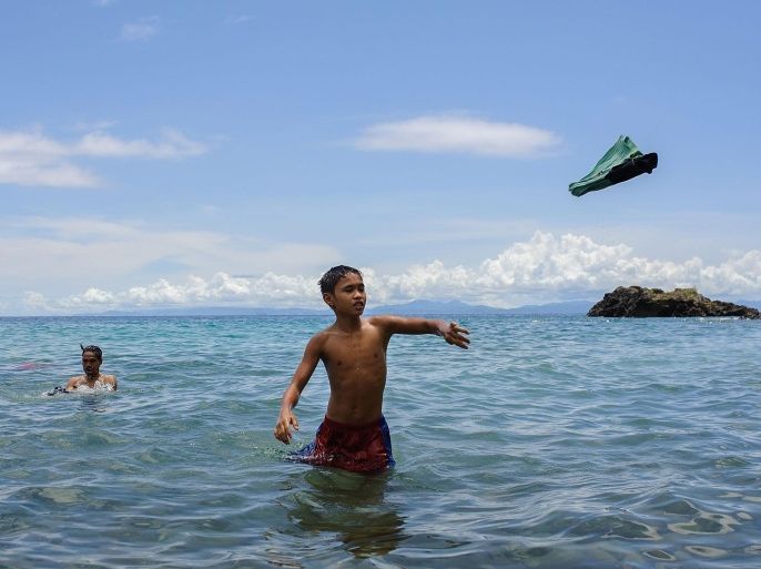 PINUT-AN, PHILIPPINES - APRIL 23: A 14-year old miner throws his t-shirt towards the shore after washing himself in the Pacific Ocean, on April 23, 2014 in Pinut-An, Philippines. Gold mining is the primary source of income for residents of Pinut-An, surpassing fishing as the leading form of employment. An average gold miner earns roughly $180 per month for working seven days a week, while the mine owner can expect to earn up to ten times that amount. Once the gold has been harvested and milled, it is delivered to buyers on the neighbouring island of Mindanao before being sold overseas or in Manila's gold markets.