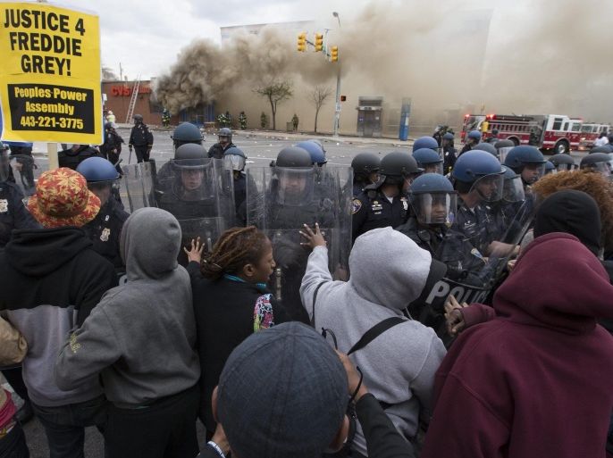Police and protesters clash in front of a building that was set on fire as protests of the death of Freddie Gray continue, in Baltimore, Maryland, USA, 27 April 2015. Freddie Gray died 19 April from a spinal injury sustained while in police custody. Gray's death has sparked protests that led to clashes with police and arrests of dozens of people over the weekend.
