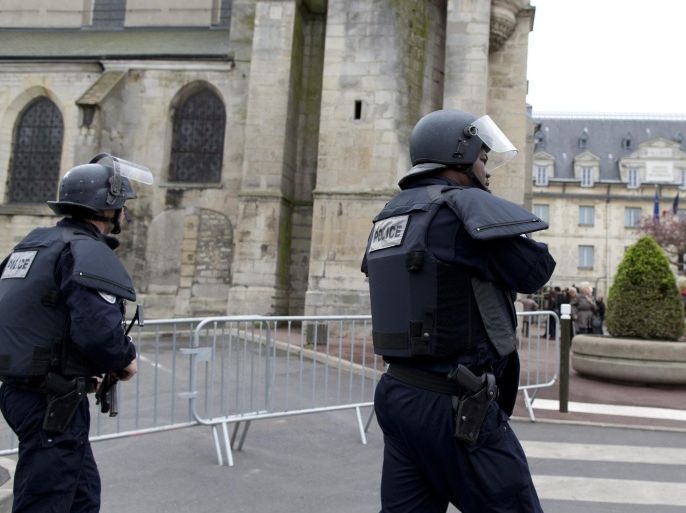 Riot policemen patrol outside the Saint-Cyr and Sainte-Julitte church in Villejuif, outside Paris, prior to a mass on April 26, 2015. An Algerian jihadist sympathiser arrested in connection with a thwarted attack on the Saint-Cyr and Sainte-Julitte church in France was charged with terror-related murder on April 24 after five days of police questioning. AFP PHOTO / KENZO TRIBOUILLARD