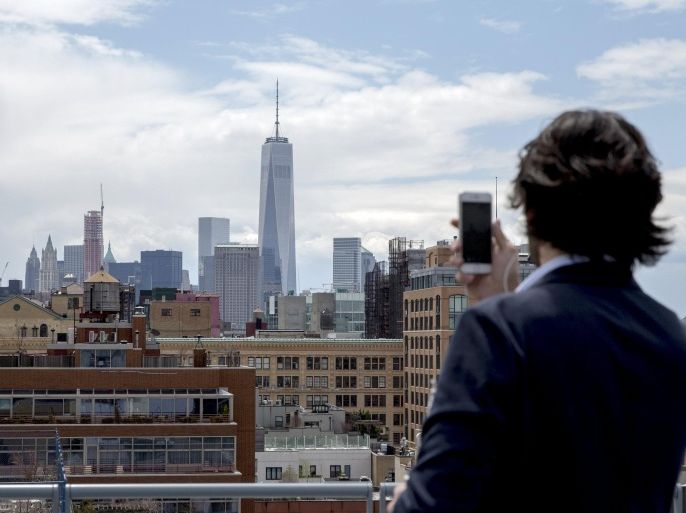 An attendee photographs One World Trade (C ) and lower Manhattan with his phone from the 8th floor cafe of The Whitney Museum of American Art in New York April 23, 2015. American art gets a new home as the Whitney Museum of American Art opens the doors to its new location in New York. REUTERS/Brendan McDermid