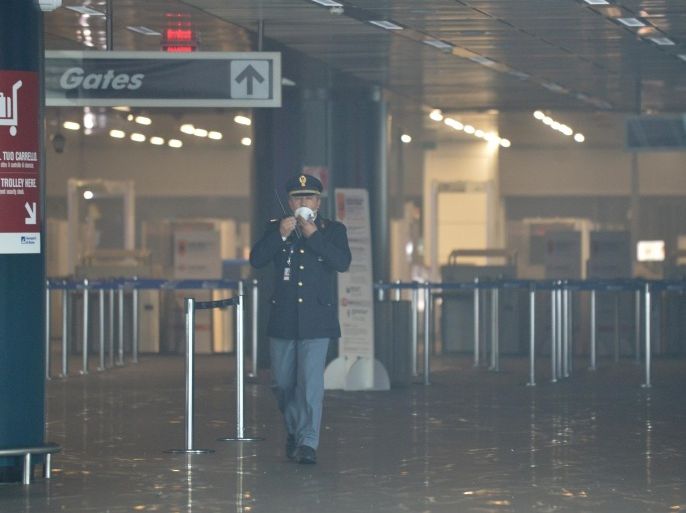 An officer wears a mask as he walks in Terminal 3 at Rome's Fiumicino international airport after a fire broke out overnight on May 7, 2015. in its main terminal for international flights. No serious injuries were reported as a result of a blaze which took hold around 5:00 am (0300 GMT) in terminal three of the Italian capital's main hub, which is located on the coast around 30km (20 miles) west of the city. Several airport employees were suffering from the effects of smoke inhalation, airport officials said. AFP PHOTO / TIZIANA FABI