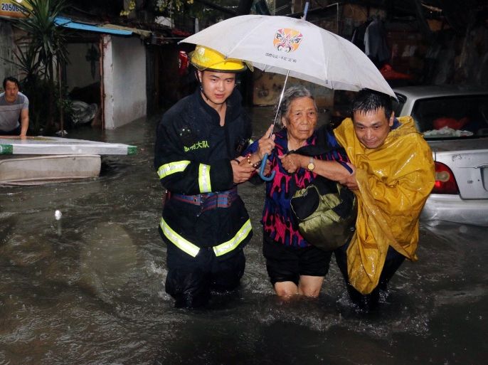 SHA4721 - Xiamen, Fujian, CHINA : This picture taken on May 20, 2015 shows rescuers helping a resident through a flooded area during an intense rainstorm that killed 7 people in Xiamen, east China's Fujian province. Rainstorms have lashed large swathes of south and central China since May 17, affecting more than a million and leaving at least 15 dead and seven missing, state media reported. AFP PHOTO CHINA OUT