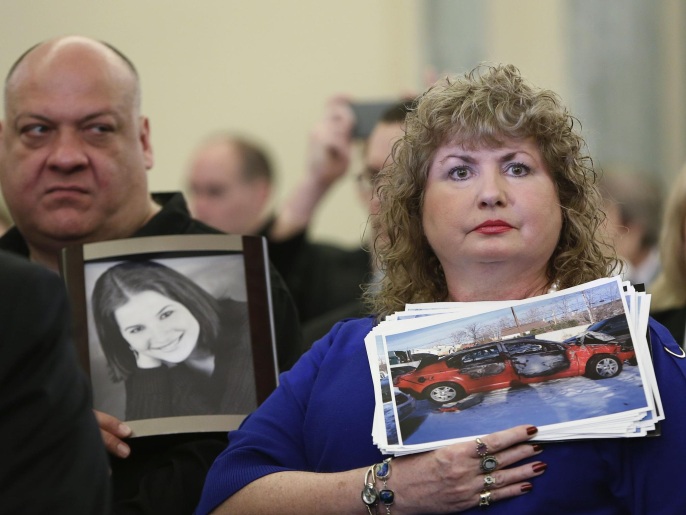 ‪أميركية تحمل صورة لسيارة ابنتها التي ماتت نتيجة فقدان السيطرة على سيارتها شيفروليه‬ (رويترز-أرشيف)