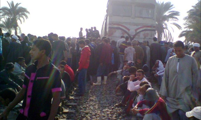 epa03474654 People stand on train tracks after a school bus collided with a train in southern Egypt in Assiut Province, about 350 kilometres south of Cairo, Egypt, 17 November 2012. According to media reports on 17 November, at least 47 people including including 44 children were killed during the accident. There were about 60 pupils on the bus when it was hit by a train at a level-crossing in the province of Assiut. ransport Minister Rashad al-Mateeni and the chief of the state-run rail authority, Mustafa Qenawi, resigned following the accident. EPA/STR BEST QUALITY AVAILABLE