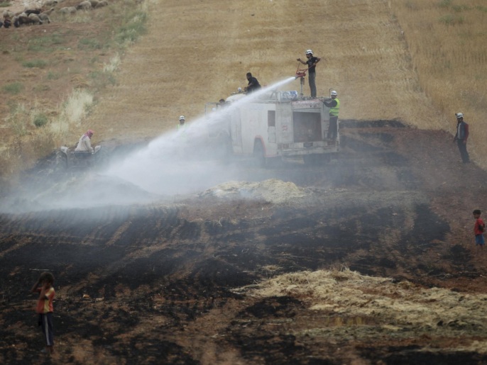 رجال إطفاء يخمدون نيرانا اشتغلت في أرض زراعية بريف إدلب نتيجة غارة جوية (رويترز)