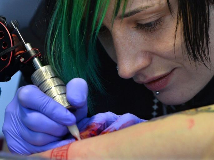 An artist tattooes an arm at the Tattoo festival in Minsk on May 30, 2015. AFP PHOTO / MAXIM MALINOVSKY