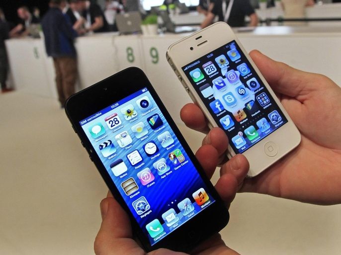A customer holds up an Apple iPhone 5 (L) and iPhone 4S in Brussels in this September 28, 2012 file photo. After five years of explosive growth sales of high-end smartphones have hit a plateau and the $2 trillion industry - telecom carriers, handset makers and content providers - is buckling up for a bumpier ride as growth shifts to emerging markets, primarily in Asia. To match Analysis SMARTPHONES-SATURATION.