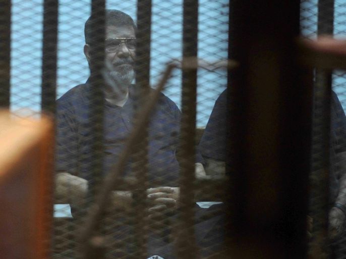 Ousted Egyptian President Mohammed Morsi sits behind glass in a courtroom, in a converted lecture hall in the national police academy in an eastern Cairo suburb, Egypt, Saturday, May 16, 2015. An Egyptian court on Saturday sentenced ousted President Mohammed Morsi to death over his part in a mass prison break that took place during the 2011 uprising that toppled Hosni Mubarak. (AP Photo/Ahmed Almalky)