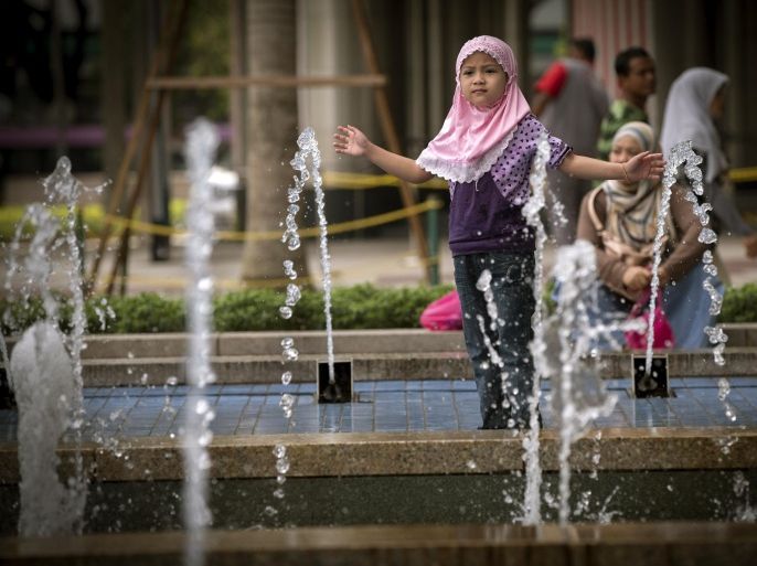 A Muslim child plays near a water fountain outside a shopping mall in Kuala Lumpur during Eid al-Fitr celebrations in Kuala Lumpur, Malaysia, Thursday, July 31, 2014. The Eid al-Fitr holiday marks the end of the Muslim holy fasting month of Ramadan. (AP Photo/Vincent Thian)