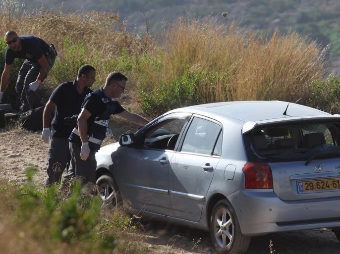 Israeli forensic police inspect a car belonging to Israeli victims of a gun attack by a Palestinian man near the Dolev settlement, northwest of Ramallah in the Israeli-occupied West Bank, on June 19, 2015. A Palestinian opened fire on two Israeli men, killing one and wounding the other, according to the Israeli authorities, in what appeared to be yet another lone-wolf attack. AFP PHOTO / ABBAS MOMANI