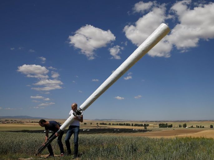 David Yanez (R) and Arturo Hidalgo set up a 6-metre (20-ft.) prototype of wind turbine without blades in a countryside at the small village in Gotarrendura, Spain, June 2, 2015. The windmill works by spinning air whirlpools in the inverted cones, aided by magnets, to create patterns of oscillation that are converted into electrical power by a generator. The same phenomena is responsible for the 'singing' of suspended power lines in the wind. Picture taken on June 2, 2015. REUTERS/Sergio Perez