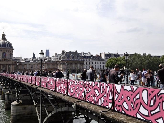 Temporary panels covered of graffiti are seen on the Pont des Arts bridge, in Paris, Wednasday, June 10, 2015. Instead of “love locks,” the Pont des Arts bridge in Paris is now decorated with love graffiti. Meanwhile, locks still hang on fencing adjacent to the bridge _ and lovestruck Paris visitors are continuing to hang padlocks on other bridges and sites around the city. (AP Photo/Thibault Camus)